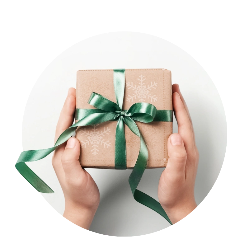 Hands holding a gift box with green ribbon and snowflake print
